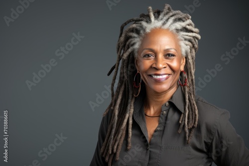 Black History Month, Pensive african american woman with dreadlocks with cheerful smile. Happy mature woman standing against a grey background.