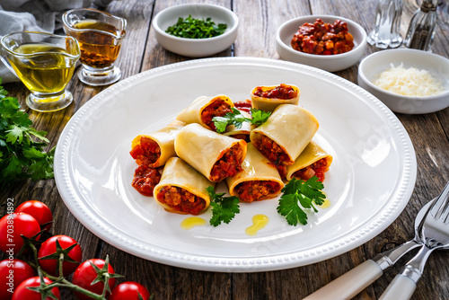 Paccheri con ragù alla bolognese - noodles with bolognese  sauce on wooden table