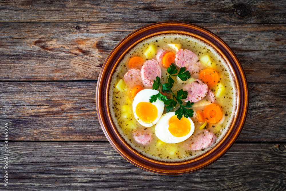 Sour rye soup with sausages and boiled eggs on wooden table Sour rye soup with sausages and boiled eggs on wooden table