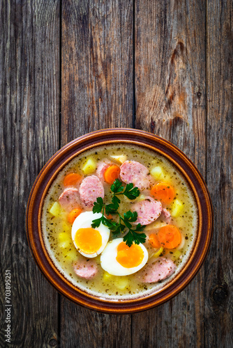  Sour rye soup with sausages and boiled eggs on wooden table