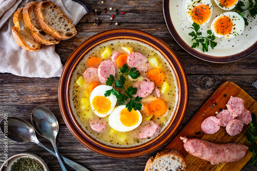  Sour rye soup with sausages and boiled eggs on wooden table