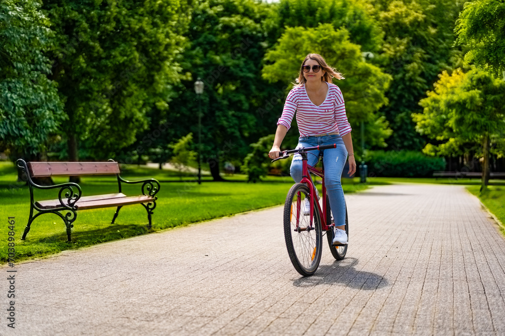 Beautiful mid adult woman riding bicycle in city park
