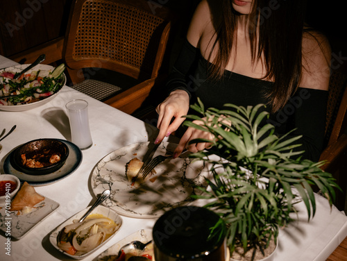 Fototapeta Naklejka Na Ścianę i Meble -  The woman eats seafood in a luxury restaurant. Dark mood.