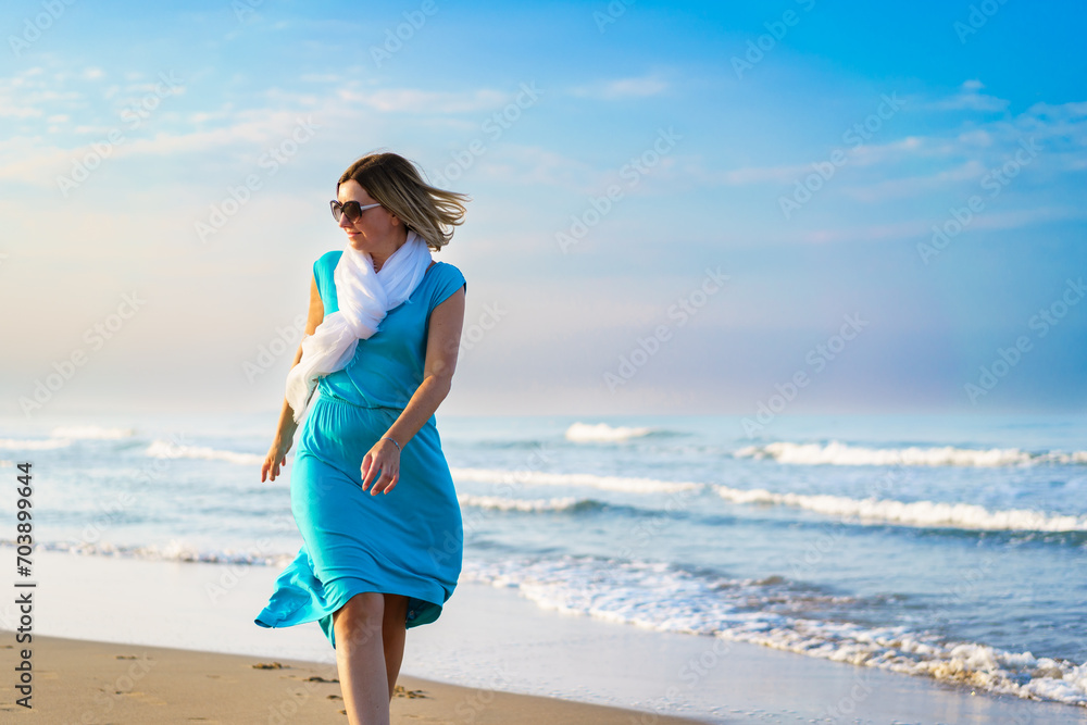 Beautiful mid adult woman walking on sunny beach 