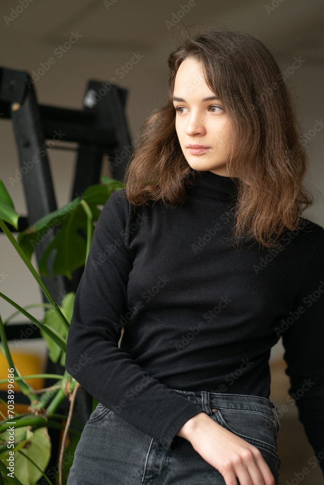 young beautiful woman posing in the studio in a black sweater near the window young beautiful woman posing in the studio in a black sweater near the window