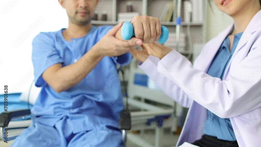 Physiotherapist female doctor in hospital is practicing physical therapy on the arm of a male patient in a wheelchair who is lifting a dumbbell. Physiotherapist female doctor in hospital is practicing physical therapy on the arm of a male patient in a wheelchair who is lifting a dumbbell.