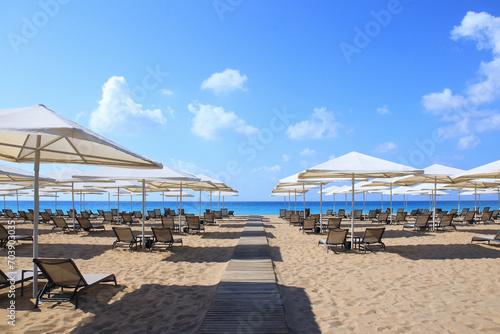 Beautiful tropical scenery. Sun beds  loungers  umbrella. Sea. Resort hotel. Rows of folded beach umbrellas and empty sunbeds on the beach. Leisure concepts. Vacation and summer concept. Travel 