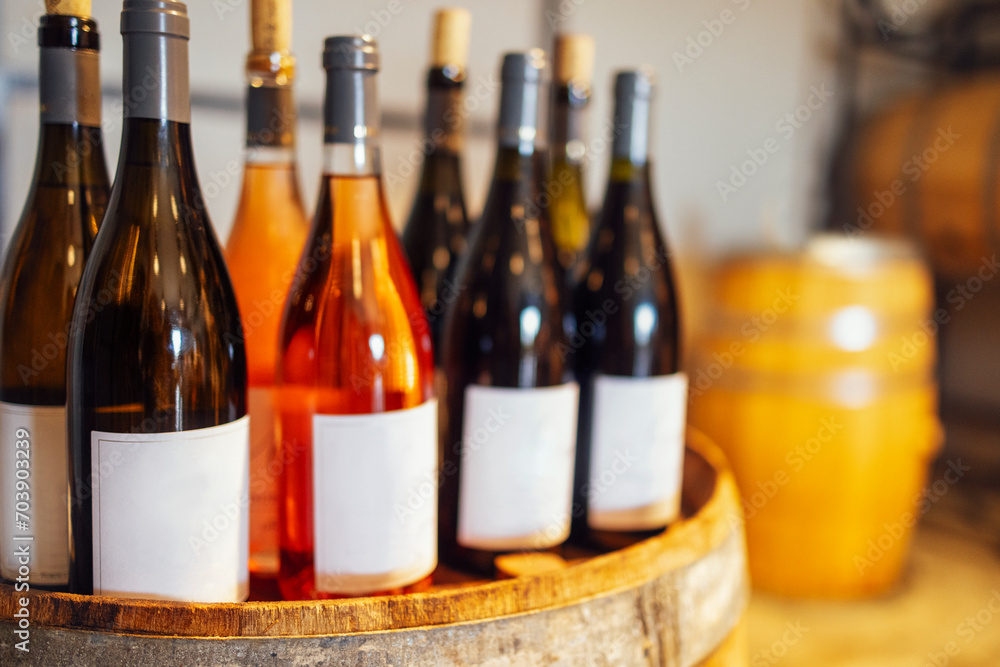 Obraz premium Close up of mockup of group of glass bottles with different wines and champagne on wooden wine barrel
