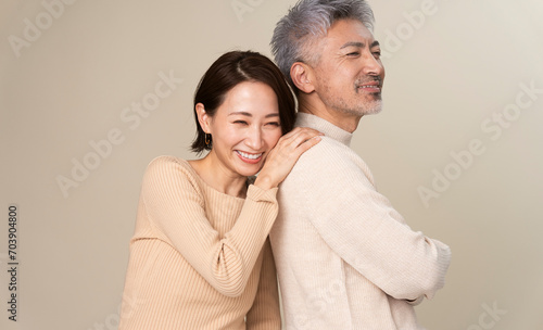 日本人ミドル世代夫婦のポートレート/男性の背中にもたれかかり微笑んでいる女性 photo