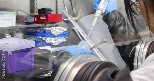 University female scientist conducts chemical experiment inside glovebox, an isolated enclosure that is designed to maintain an inert atmosphere.