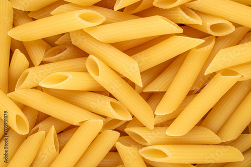 Raw pasta, penne, macro, top view.