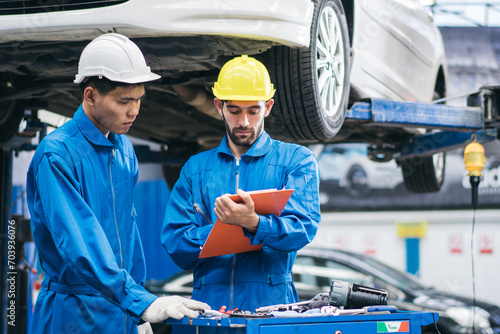 Automotive mechanic discussing on car damage checklist with assistant at auto garage shop. Transport industry, repair and maintenance career. after service after service photo