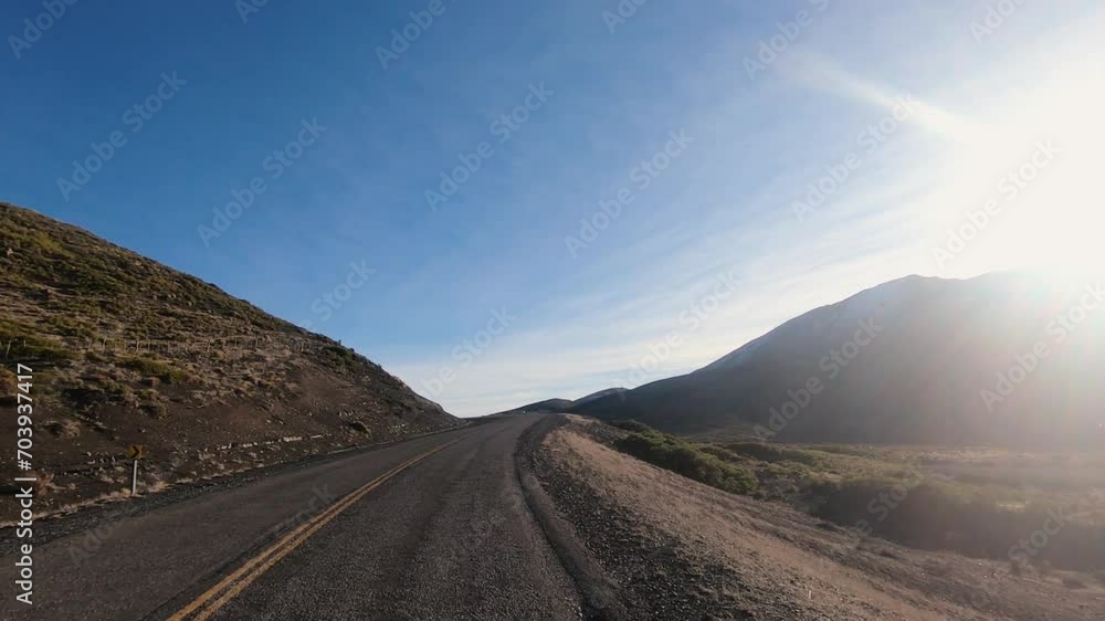 Point of view of a car traveling along the asphalt road in the desert and mountains at sunset. The hiding sun in the horizon. Point of view of a car traveling along the asphalt road in the desert and mountains at sunset. The hiding sun in the horizon.