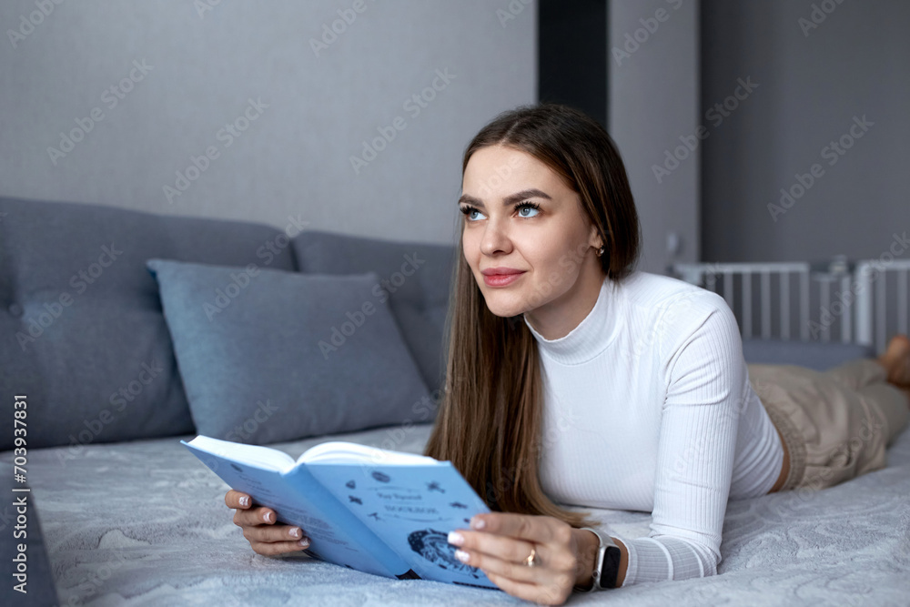 Beautiful sexy adult woman spends her weekend in a comfortable bedroom, lying on the bed, reading a book and enjoying classic literature. Beautiful sexy adult woman spends her weekend in a comfortable bedroom, lying on the bed, reading a book and enjoying classic literature.