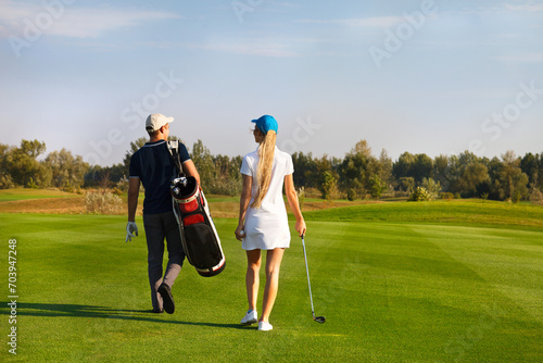 Couple playing golf on a golf course walking to the next hole