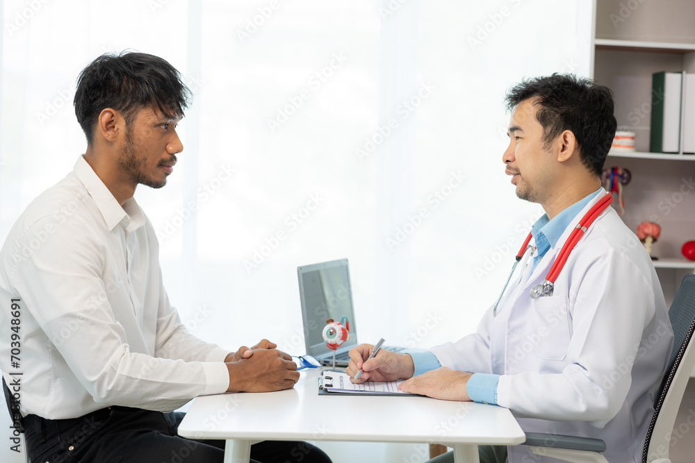 Obraz premium Close-up of an Asian male doctor showing an eyeball model and explaining eye diseases to a male patient in hospital. health care concept