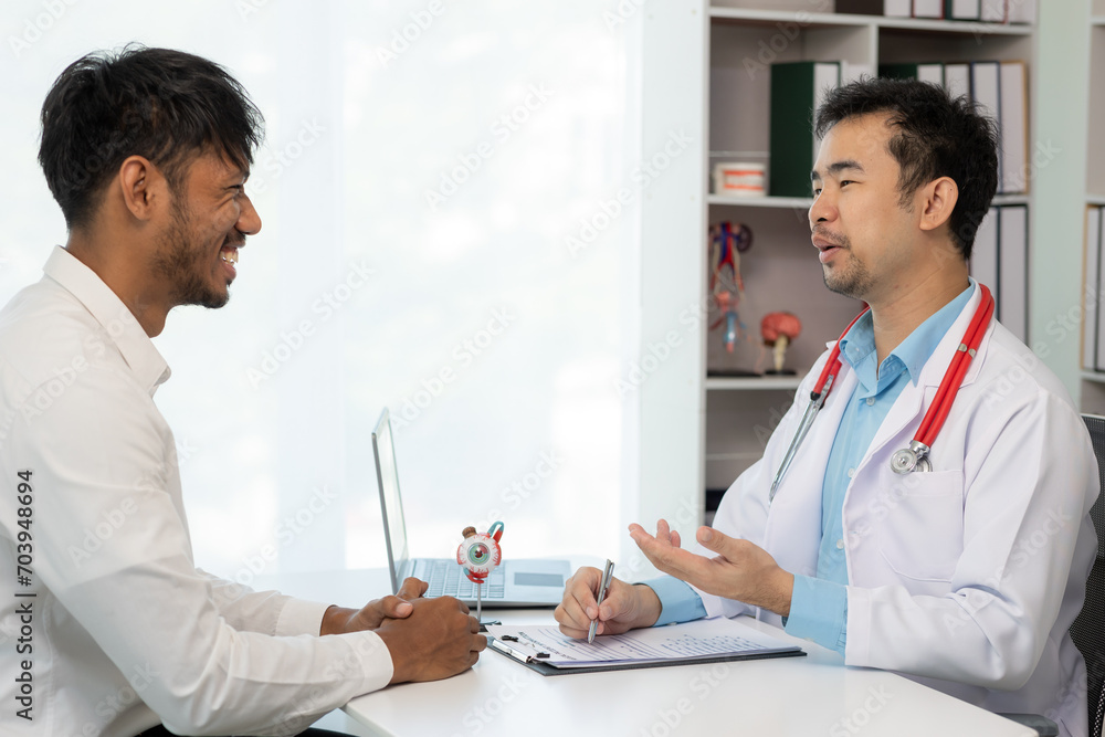 Close-up of an Asian male doctor showing an eyeball model and explaining eye diseases to a male patient in hospital. health care concept