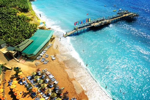 Aerial View of Beautiful Summer Beach with People, Blue Sea, Pier and Umbrellas. Travel and Vacation Concept.