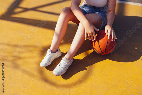 Stylish cool teen girl gathering at basketball court, playing basketball outdoors © Dasha Petrenko