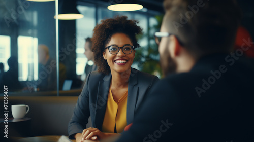 View above man's shoulders at the woman in formal business wear is engaged in a pleasant conversation with a colleague, conveying a positive, collaborative professional meeting photo