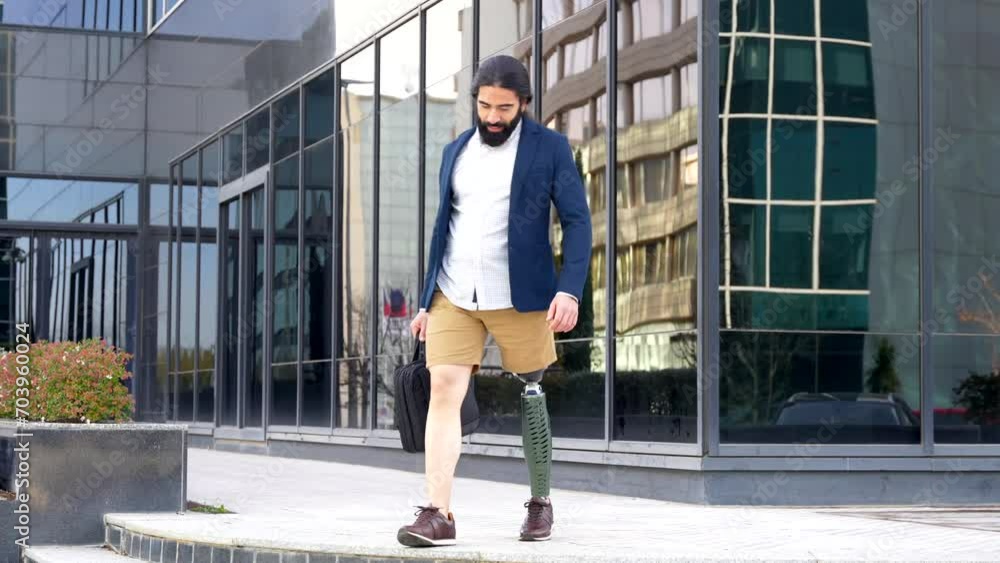 Businessman with prosthetic leg carrying a laptop bag walking along the street Businessman with prosthetic leg carrying a laptop bag walking along the street