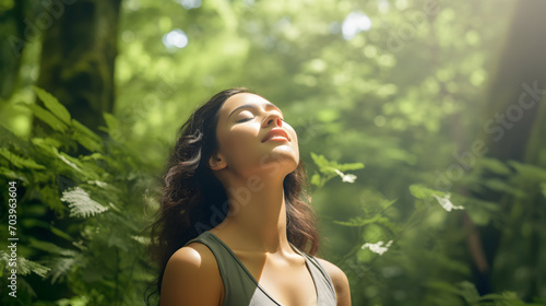 Relaxed woman breathing fresh air in a green forest photo