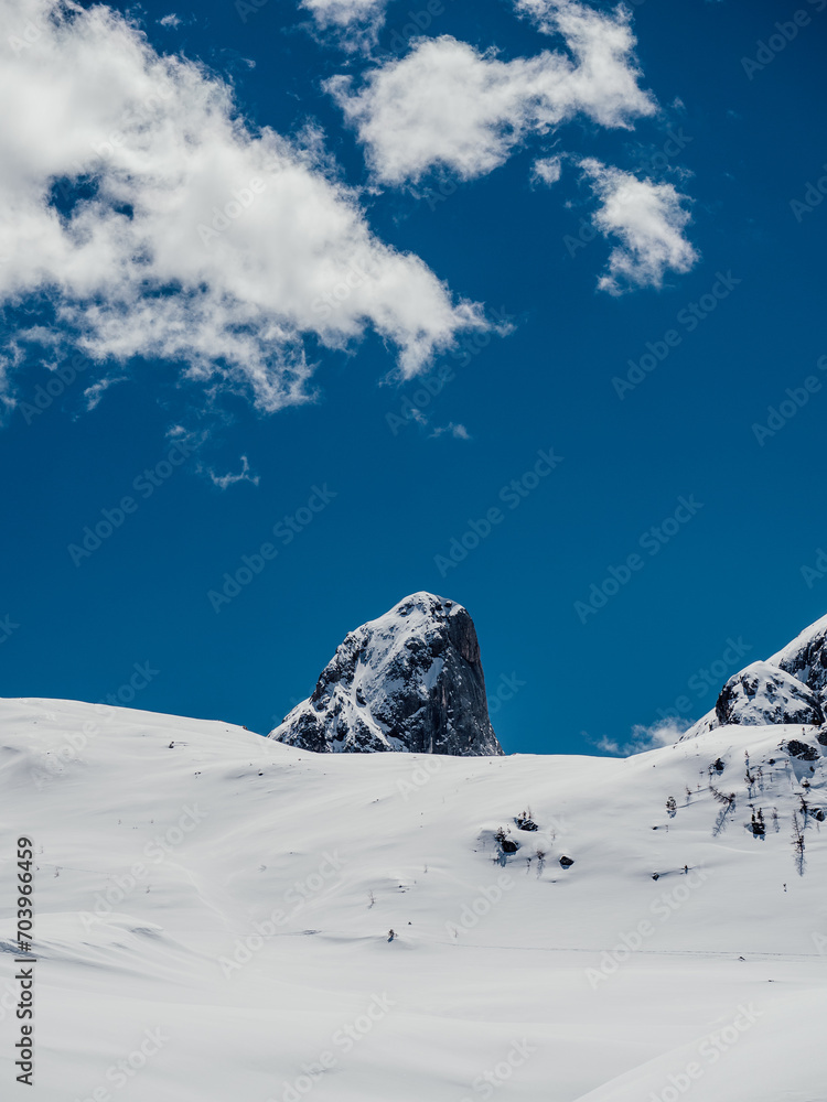 a mountain covered in snow with some clouds and blue skies