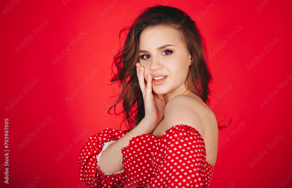 Attractive elegant brunette female posing in red polka dot dress in studio Attractive elegant brunette female posing in red polka dot dress in studio