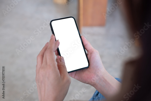 Mockup cell phone, woman's hand holding using mobile phone at coffee shop with copy space, white blank screen for text, mobile app design 