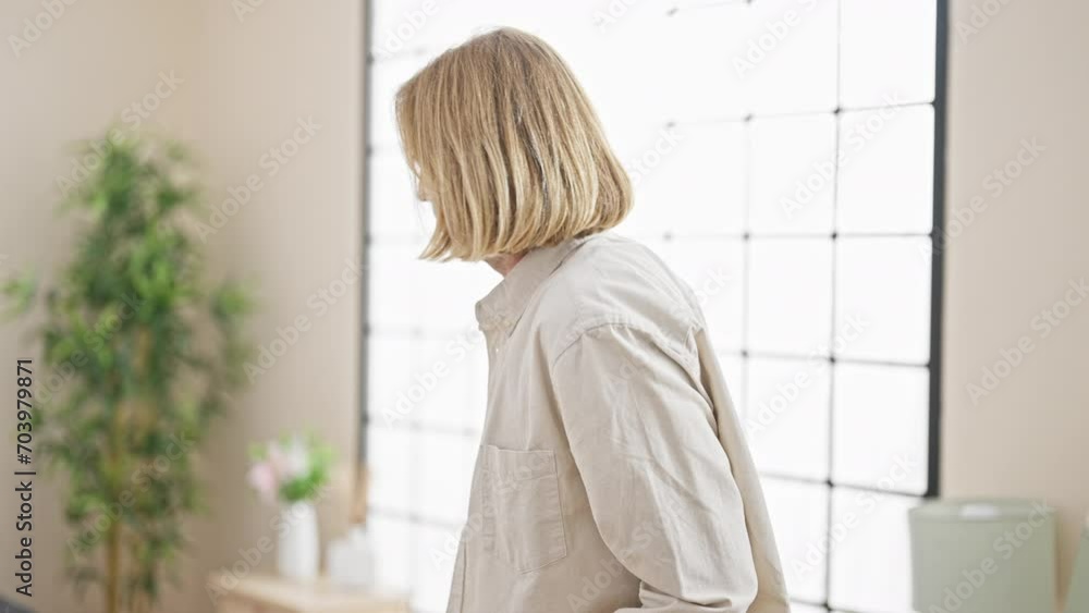 Injured man with long blond hair limps using crutches in a modern bedroom, showing pain and discomfort. Injured man with long blond hair limps using crutches in a modern bedroom, showing pain and discomfort.