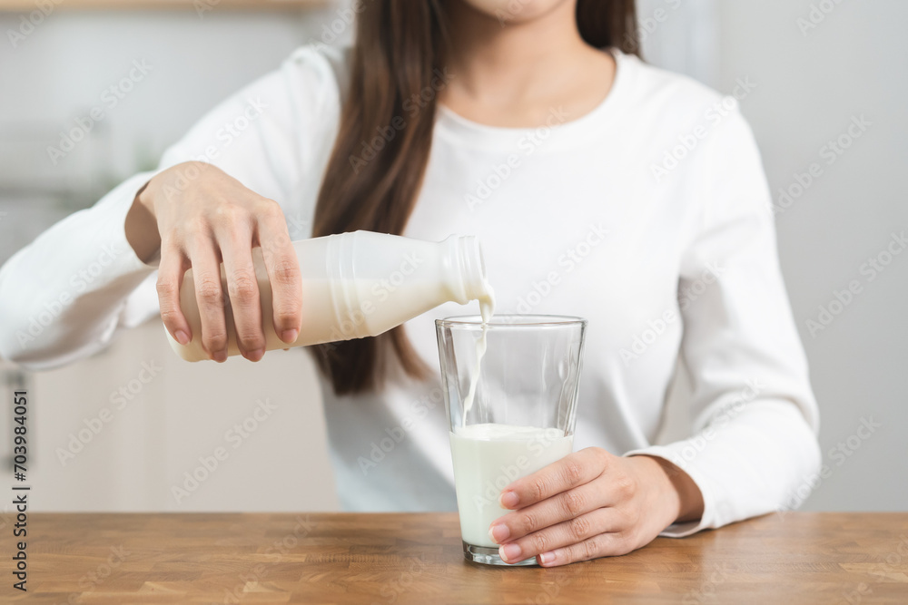 Health care, asian young woman, girl hand pouring of fresh, dairy milk from bottle into glass, drinking and eating breakfast in morning at kitchen home. Calcium, protein for healthy lifestyle people Health care, asian young woman, girl hand pouring of fresh, dairy milk from bottle into glass, drinking and eating breakfast in morning at kitchen home. Calcium, protein for healthy lifestyle people