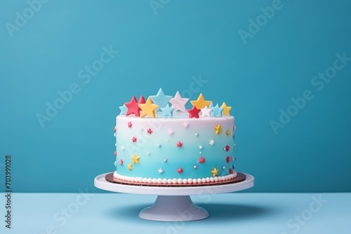  a blue cake with white frosting and stars on top on a white cake stand on a blue table against a blue background with a blue wall in the background.