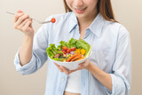 Diet concept, happy smile asian young woman use fork to prick tomato, fresh vegetable or green salad, eat nutrition food isolated on background, low fat to good body, getting weight loss for healthy.