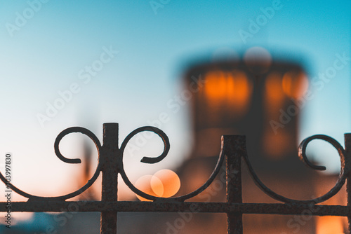 close-up photo of a curved metal barrier. blurred image of the towers of la rochelle in the background photo