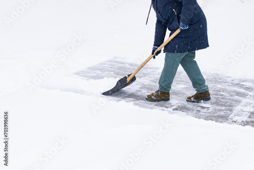 an unrecognizable man cleans snow with a shovel in a snowfall