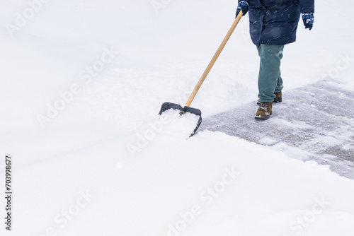 an unrecognizable man cleans snow with a shovel in a snowfall