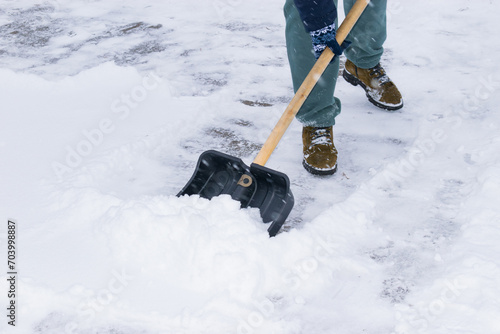 an unrecognizable man cleans snow with a shovel in a snowfall. close-up
