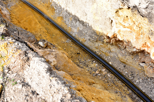 A plastic black gas pipe at the bottom of the trench. A dug trench for laying a gas pipe.