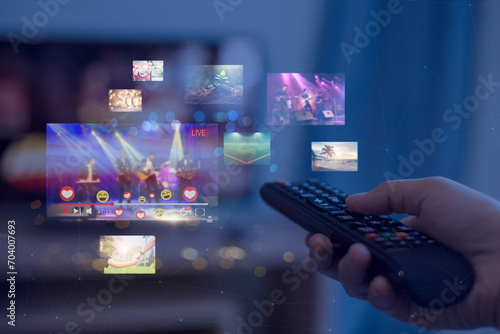 Close-up of hands using remote smart tv on blurred smart tv with video on demand as background photo