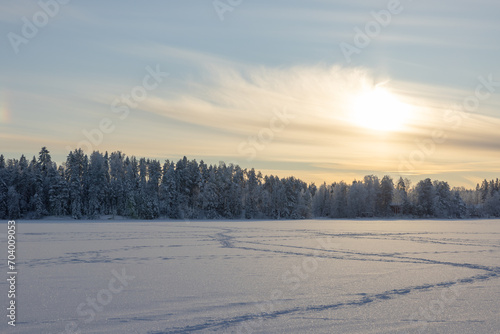 Very cold January winter day scenery (-21ºC). Sun is shining just above horizon behind the clouds. 