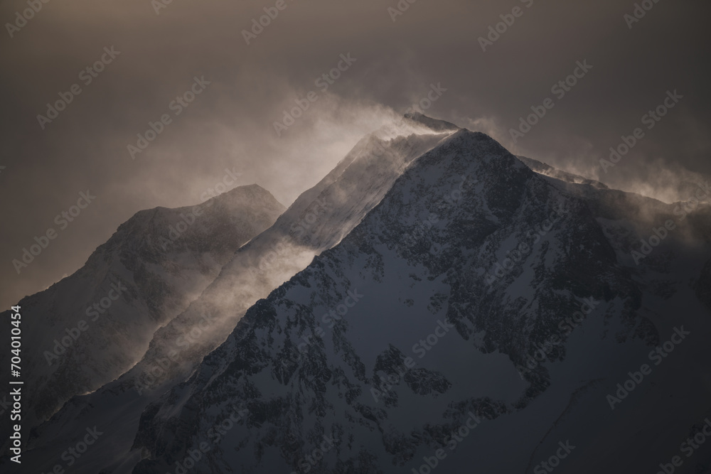 strong south wind in the alps at a cloudy and sunny winter day in the national park hohe tauern in austria