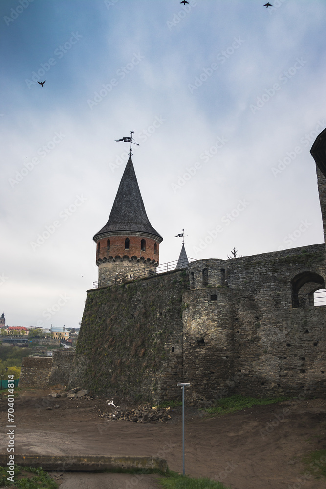 The part of Old Kamianets-Podilskyi Castle under a cloudy sky. Powerful bastions and towers of the fortress located among the picturesque nature in the historic city of Kamianets-Podilskyi,
