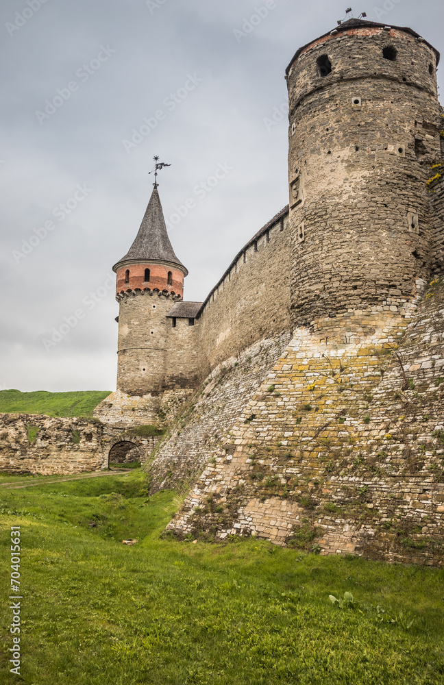 The part of Old Kamianets-Podilskyi Castle under a cloudy sky. Powerful bastions and towers of the fortress located among the picturesque nature in the historic city of Kamianets-Podilskyi,