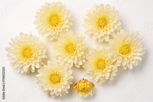  a group of yellow flowers sitting on top of a white table next to a vase of flowers on top of a white table next to a vase with a yellow flower in the middle.