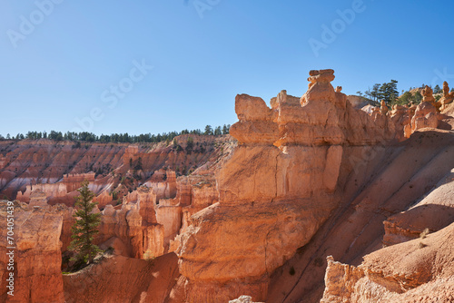 A rock formation at the edge of the Bryce Canyon amphitheater. Colorful hoodos and white layers are seen in the distance.