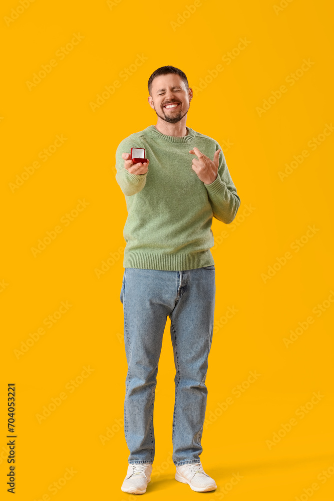 Young man with engagement ring crossing fingers on yellow background Young man with engagement ring crossing fingers on yellow background