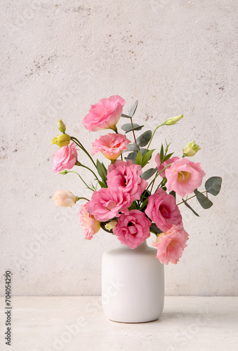 Vase with beautiful pink eustoma flowers and eucalyptus on white background photo