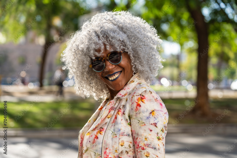 Stylish, smiling afro lady with grey afro hairstyle in sunny city Stylish, smiling afro lady with grey afro hairstyle in sunny city