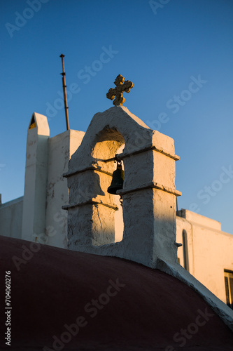 the last sunbeam hitting the small campanille of a small white church in the Mykonos island aegean sea Greece photo