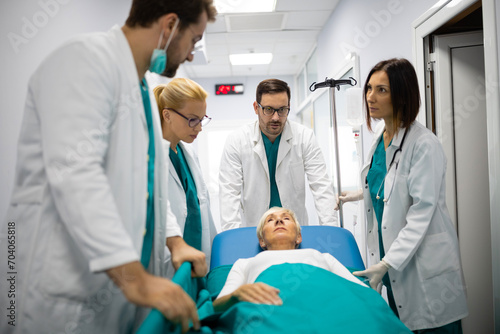 Patient hospital bed moved by medical staff to operating room. Surgeons pushing patient on bed into surgery.Medical team moving old patient on gurney through hospital corridor for an urgent operation